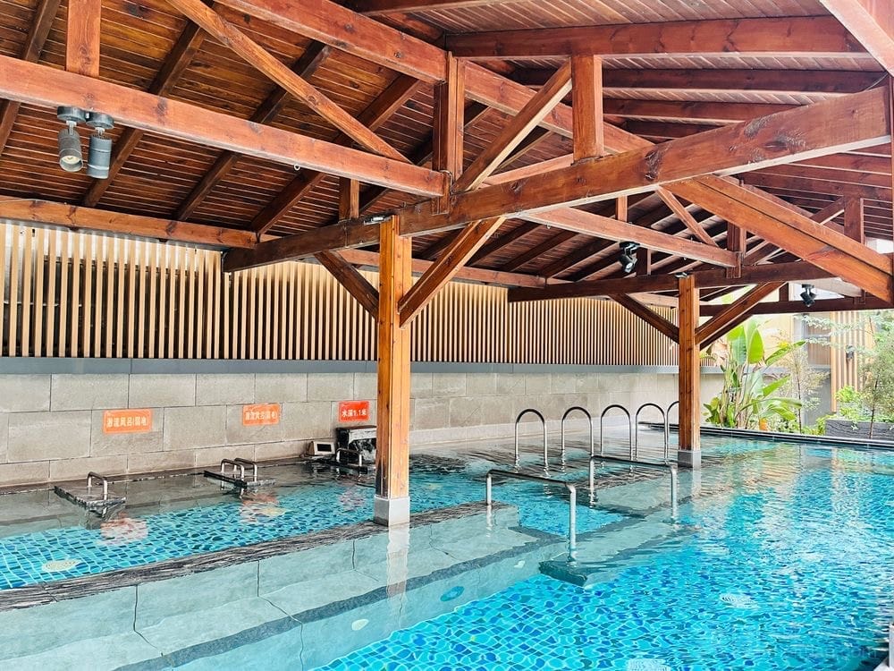 La vasca azzurra della SPA di Chengdu sotto le capriate di legno.